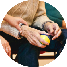 An elderly woman is holding a ball in her hands.